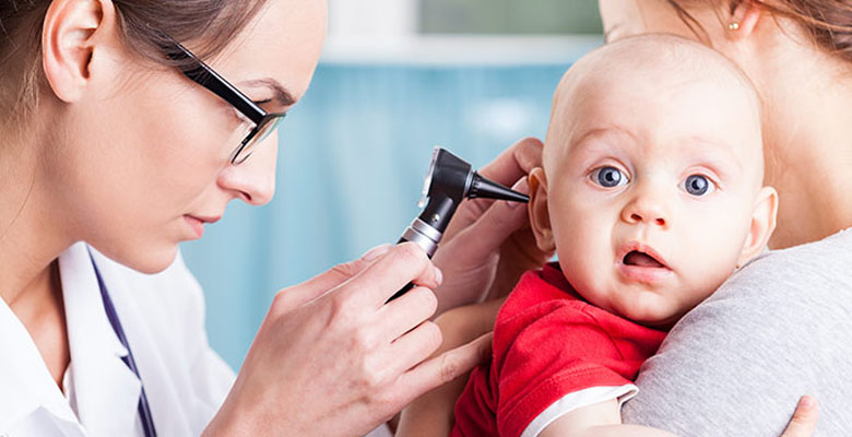 Revisión de oídos a un bebé en consultorio médico.