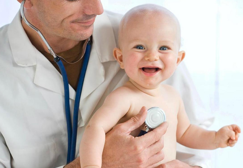 Médico cargando bebé y revisando con un estetoscopio