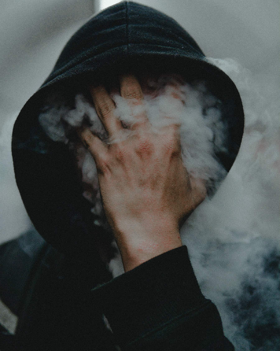 retrato de hombre con la cara cubierta por humo y su mano izquierda