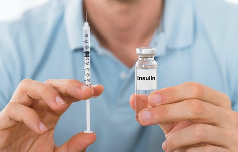 Detalle de un hombre sosteniendo jeringa y ampolleta con insulina.