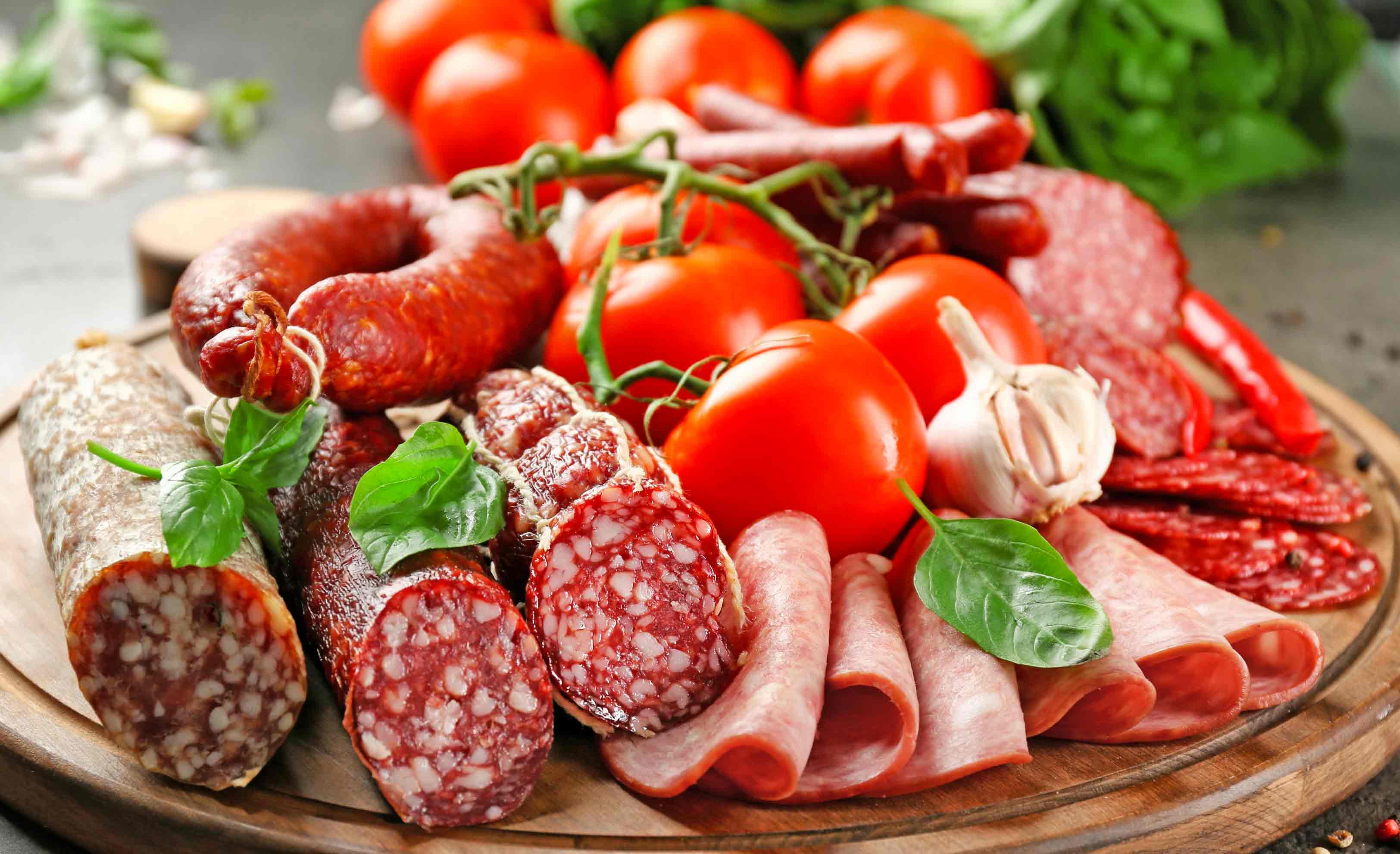 Plato con embutidos, carnes frías y tomates, que no son recomendados durante el tratamiento de cistitis.